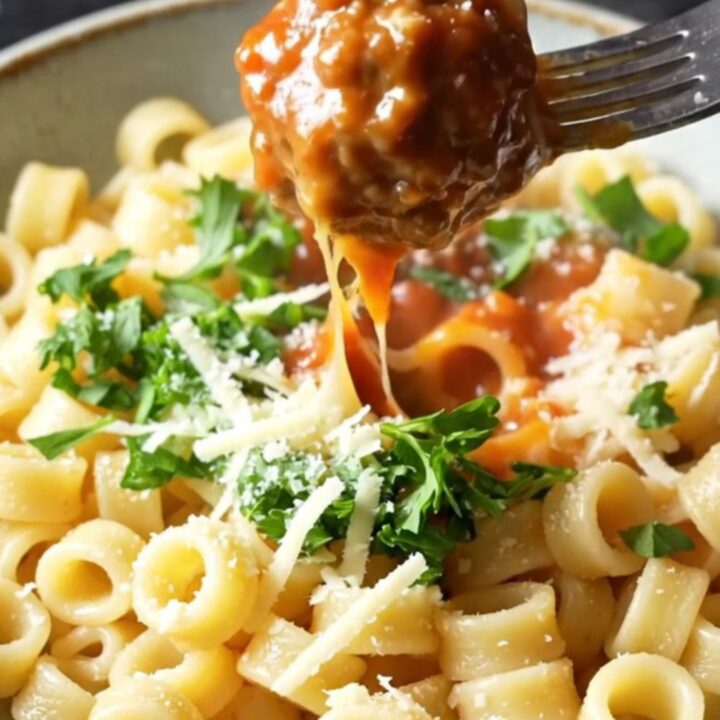 One-pan meatball ring pasta with whole tomatoes and melted mozzarella in a skillet
