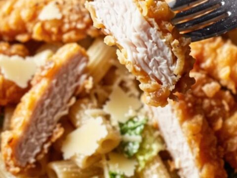 Golden fried chicken strips on a bed of creamy Caesar pasta salad with Parmesan
