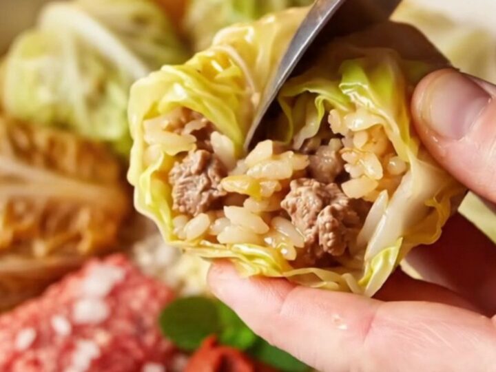 Golden stuffed cabbage cups in a baking dish with tomato broth