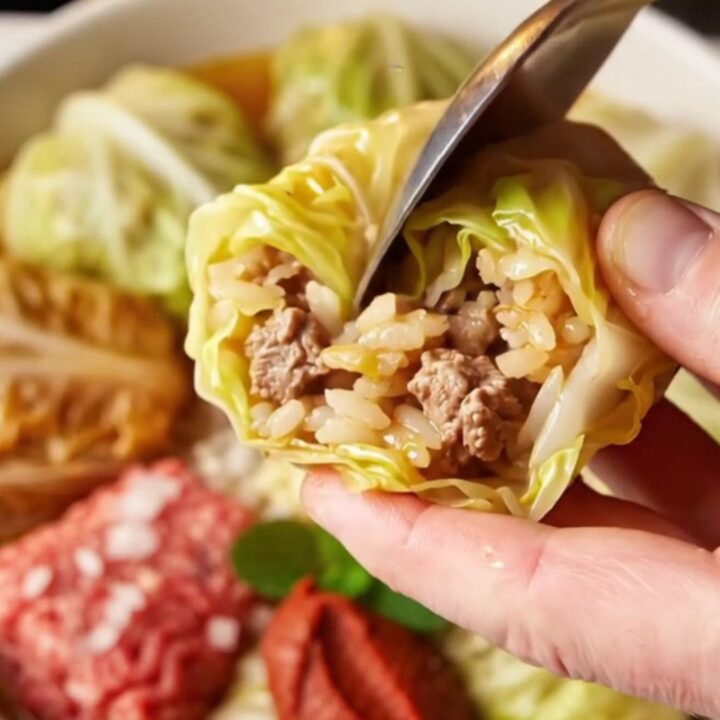 Golden stuffed cabbage cups in a baking dish with tomato broth