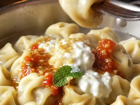 Golden manti dumplings on a ceramic dish with garlic yogurt and paprika butter sauce