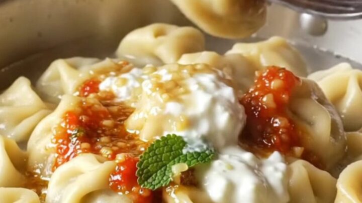 Golden manti dumplings on a ceramic dish with garlic yogurt and paprika butter sauce