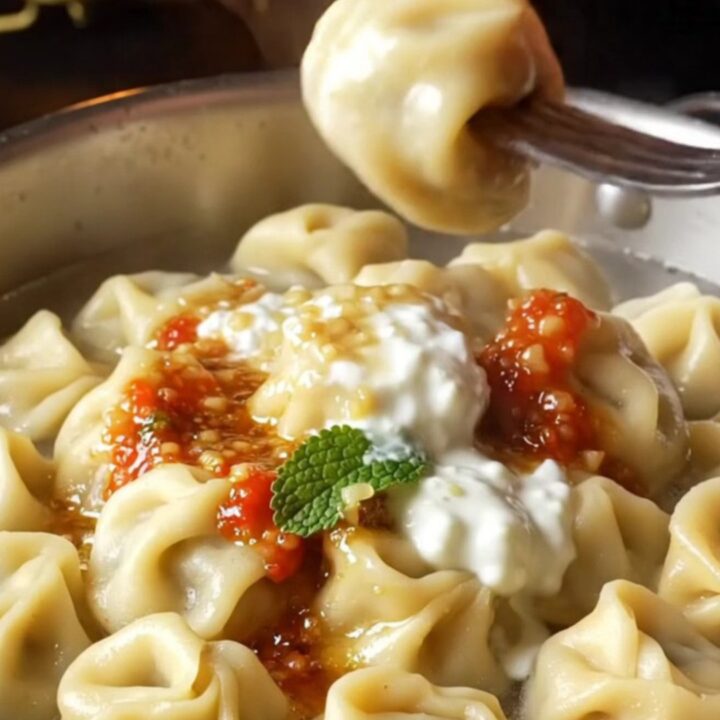 Golden manti dumplings on a ceramic dish with garlic yogurt and paprika butter sauce