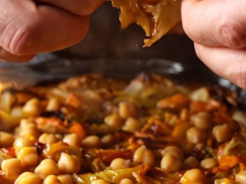 Baked chickpea tava in a glass dish with caramelized peppers and tomatoes, served with flatbread