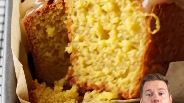 Whole lemon cake with white glaze and lemon zest on a cooling rack
