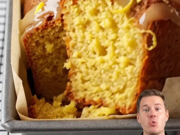 Whole lemon cake with white glaze and lemon zest on a cooling rack