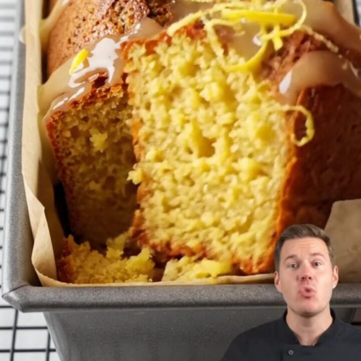 Whole lemon cake with white glaze and lemon zest on a cooling rack