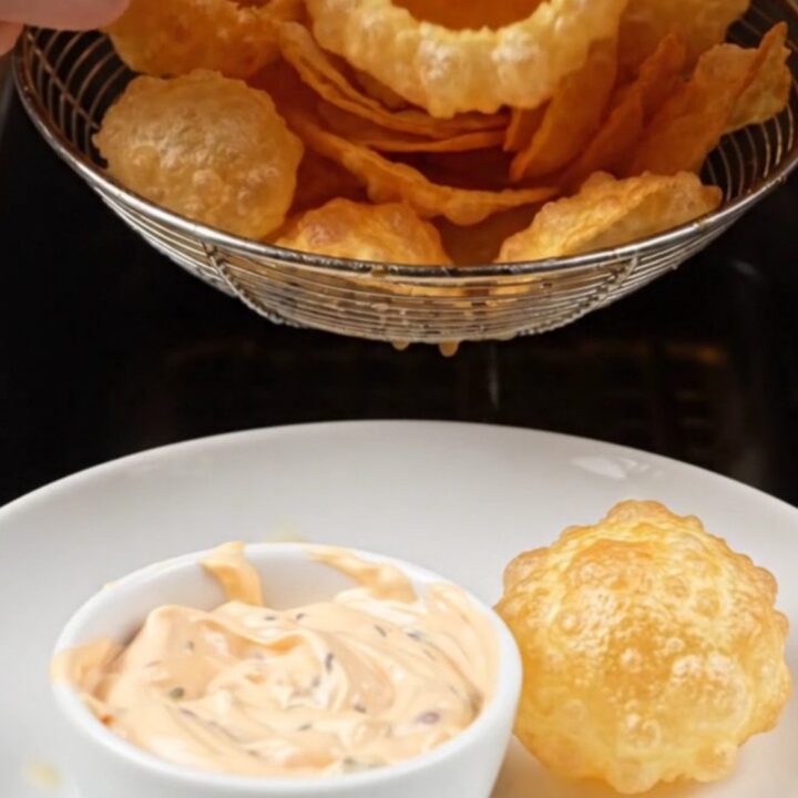 Golden smiley face chips piled in a bowl with a side of dip