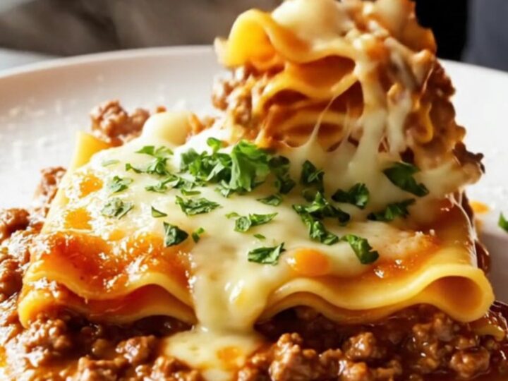 A skillet lasagna with melted cheese and parsley, served on a plate