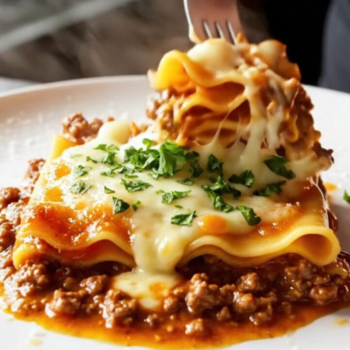 A skillet lasagna with melted cheese and parsley, served on a plate