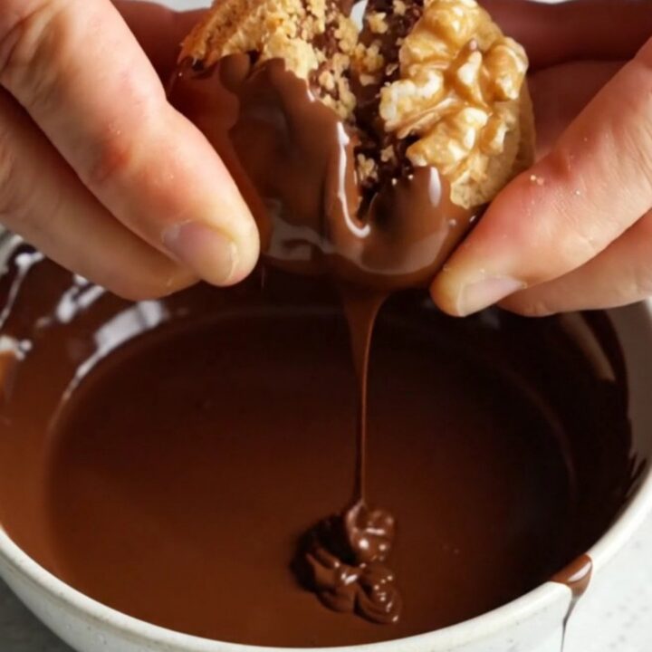 Chocolate-dipped walnut shortbread wafer cookies arranged on a parchment-lined tray
