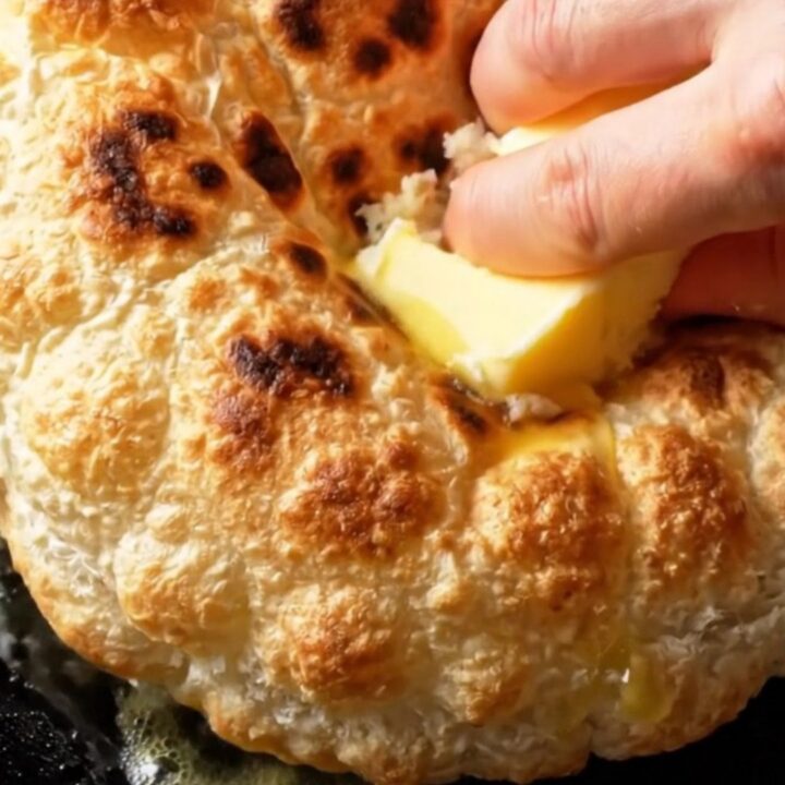 Golden puffy flatbread brushed with melted butter on a wooden board