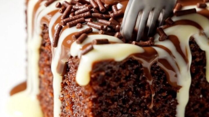 A rich chocolate skillet cake topped with glossy ganache, chocolate sprinkles, and a fanned strawberry