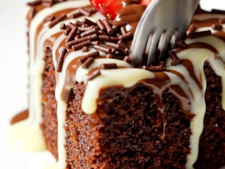 A rich chocolate skillet cake topped with glossy ganache, chocolate sprinkles, and a fanned strawberry