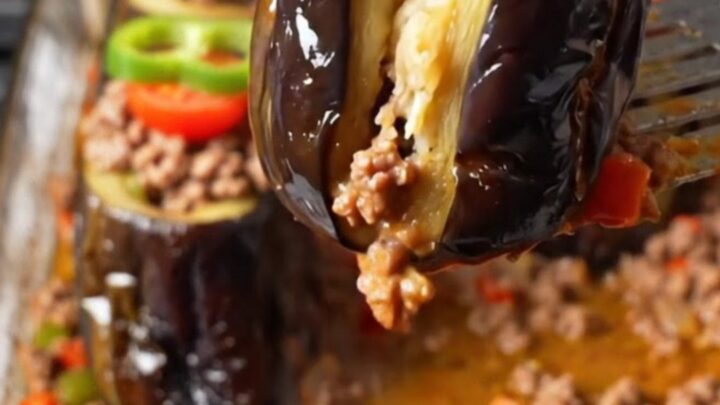 Baked stuffed eggplant cups with spiced beef in a tomato broth, garnished with pepper rings