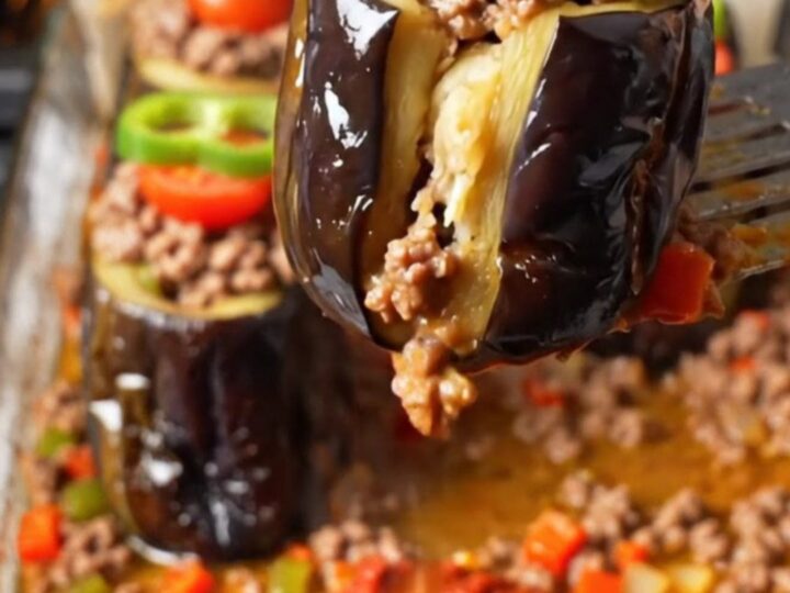 Baked stuffed eggplant cups with spiced beef in a tomato broth, garnished with pepper rings