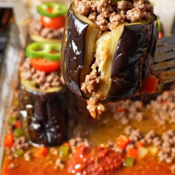 Baked stuffed eggplant cups with spiced beef in a tomato broth, garnished with pepper rings