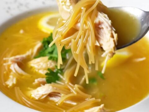 A bowl of Turkish chicken vermicelli soup garnished with fresh parsley and lemon wedge