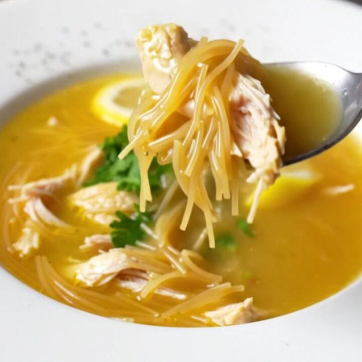 A bowl of Turkish chicken vermicelli soup garnished with fresh parsley and lemon wedge