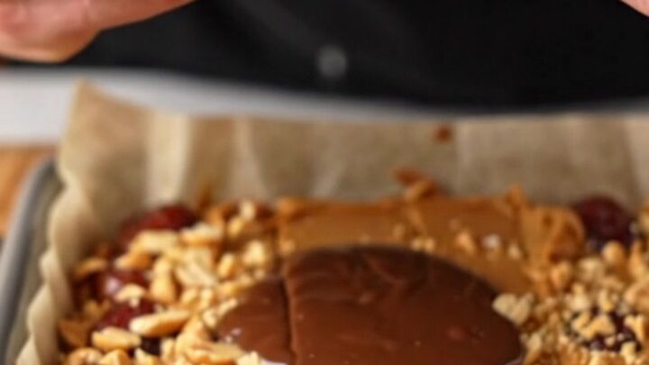 Squares of chocolate peanut butter date bark on a cutting board, showing layers of dark chocolate, peanut butter, and dates.