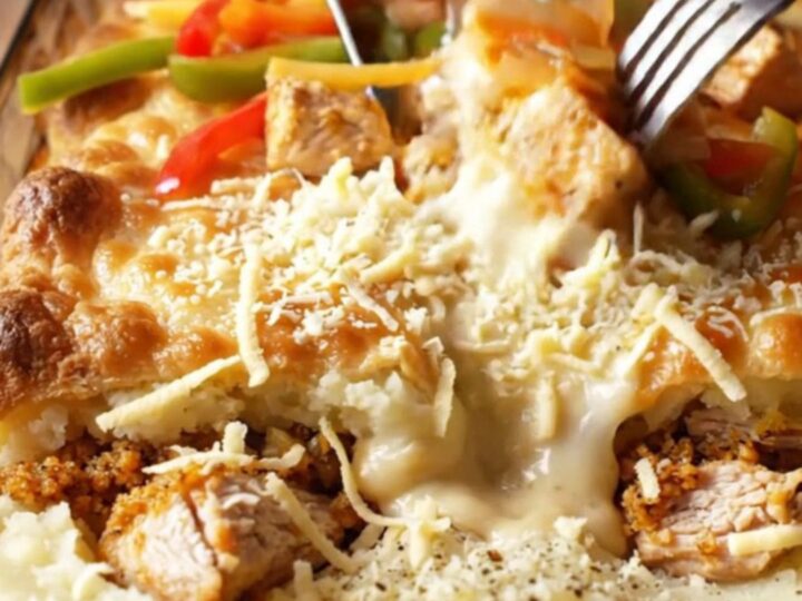 A golden, bubbly casserole in a glass dish, showing layers of mashed potato, chicken