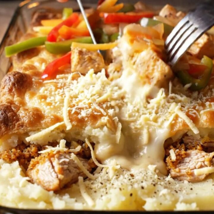 A golden, bubbly casserole in a glass dish, showing layers of mashed potato, chicken
