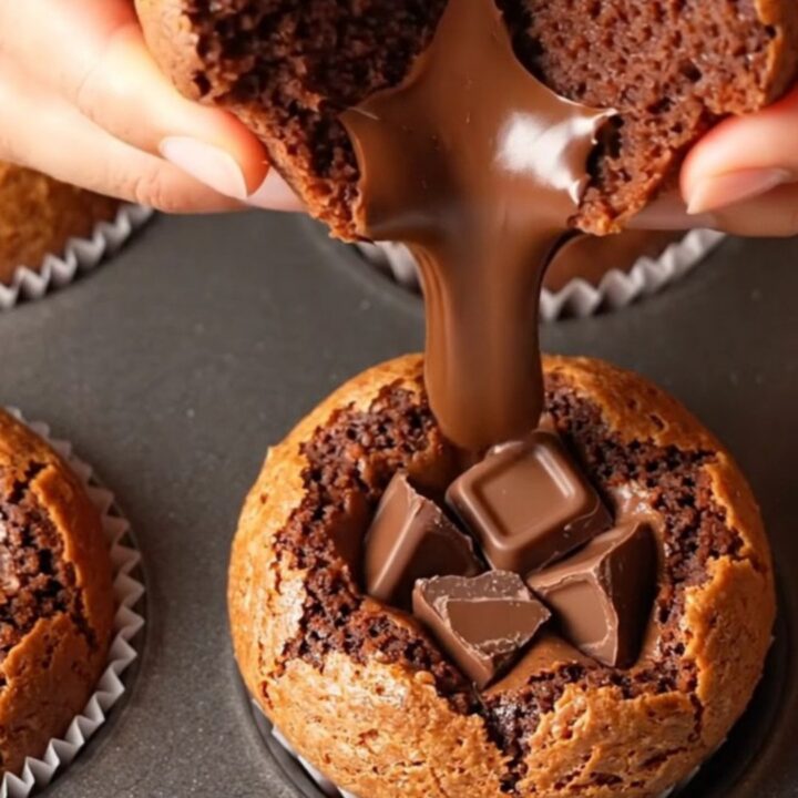 Fudgy brownie muffin broken in half showing gooey chocolate center