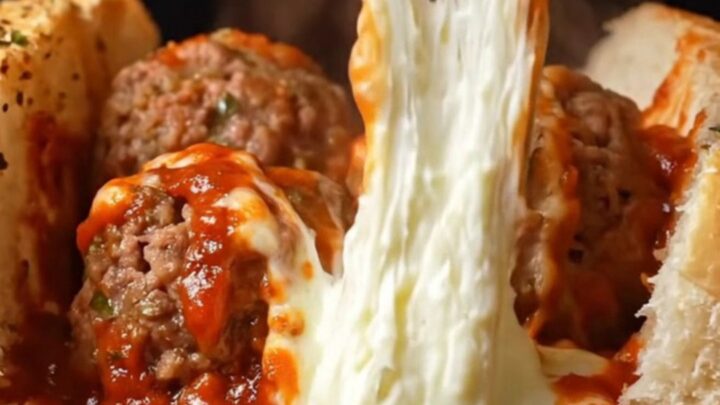 Giant meatball sub with molten mozzarella pull and marinara sauce, on a baking sheet