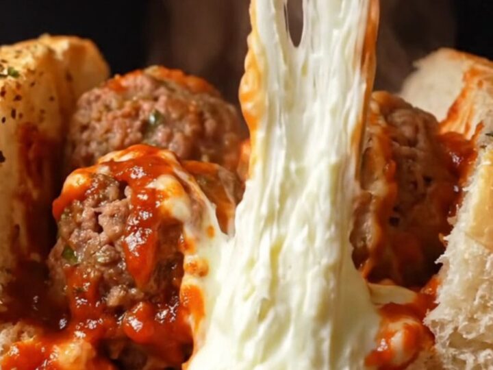 Giant meatball sub with molten mozzarella pull and marinara sauce, on a baking sheet