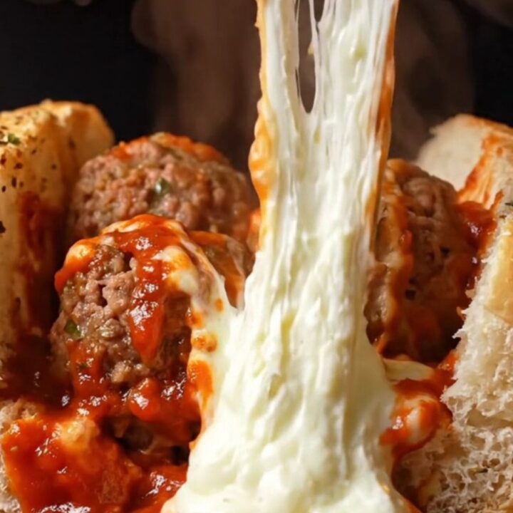 Giant meatball sub with molten mozzarella pull and marinara sauce, on a baking sheet