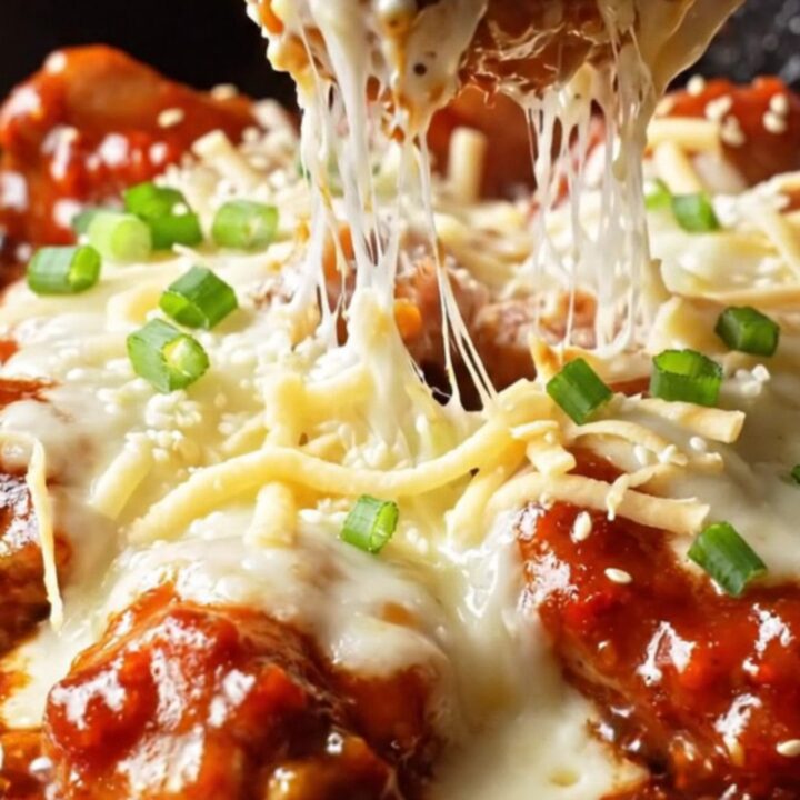 Skillet of Korean cheesy fire chicken with bubbling mozzarella and charred edges