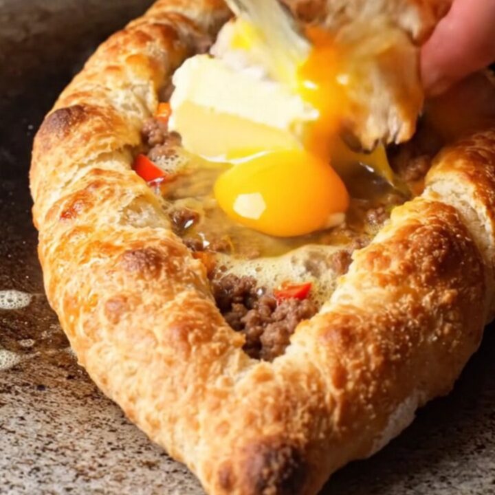 Boat-shaped Turkish pide with blistered crust, spiced beef, melted butter, and glossy egg yolk
