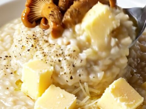 Creamy wild mushroom and Taleggio risotto topped with seared chanterelles and truffle oil in a skillet