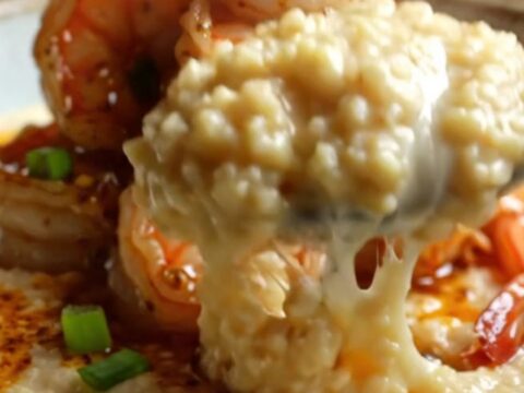 Creamy Cajun garlic shrimp and white cheddar grits in a shallow bowl, topped with green onions
