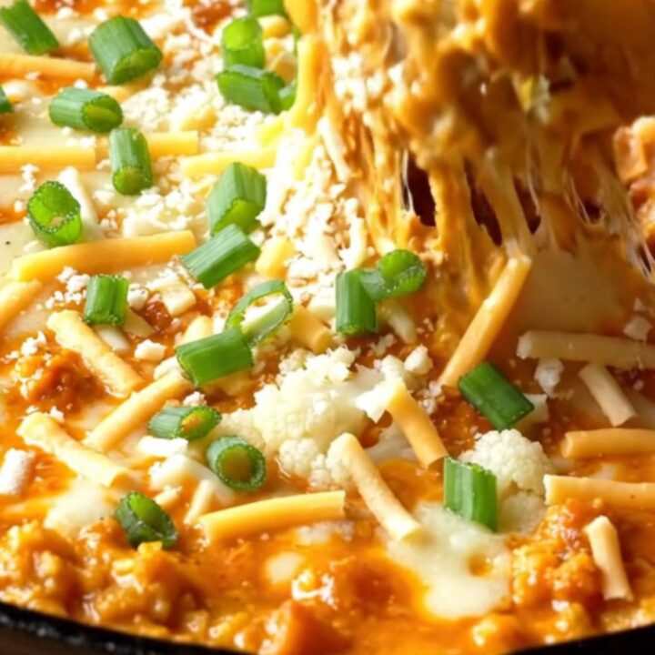 Skillet of cheesy buffalo cauliflower dip with toasted baguette slices
