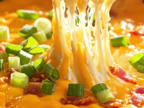 Loaded skillet baked potato dip with melted cheddar and bacon, served hot with potato chips.
