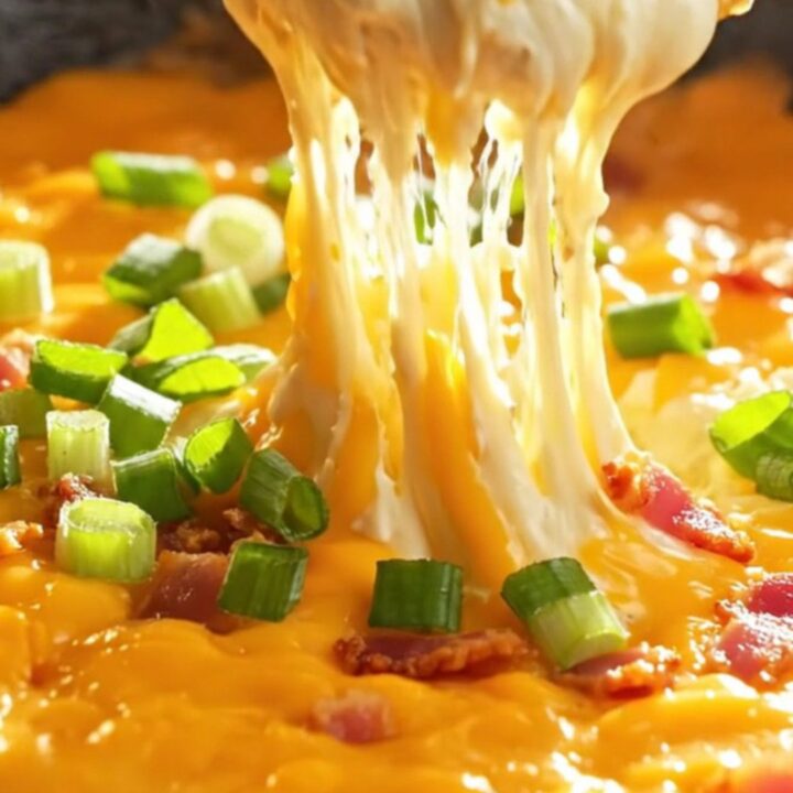 Loaded skillet baked potato dip with melted cheddar and bacon, served hot with potato chips.