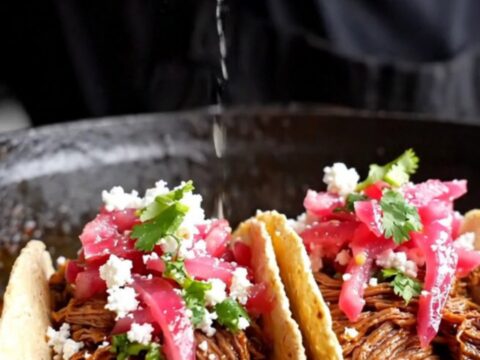 Slow-cooked beef barbacoa tacos topped with pickled red onions, cotija cheese, and cilantro on corn tortillas.