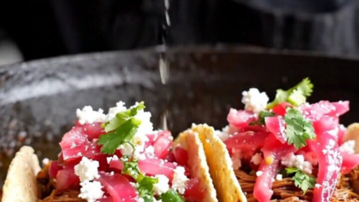 Slow-cooked beef barbacoa tacos topped with pickled red onions, cotija cheese, and cilantro on corn tortillas.