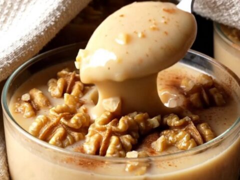 A glass bowl of Turkish fig milk pudding topped with cinnamon and chopped walnuts