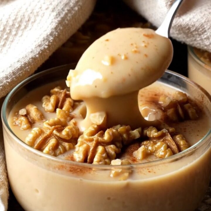 A glass bowl of Turkish fig milk pudding topped with cinnamon and chopped walnuts
