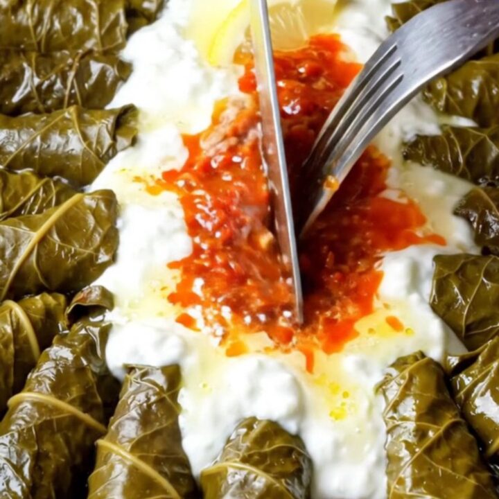 A pot of Turkish stuffed grape leaves with lemon butter sauce, drizzled with garlic yogurt and red pepper butter.