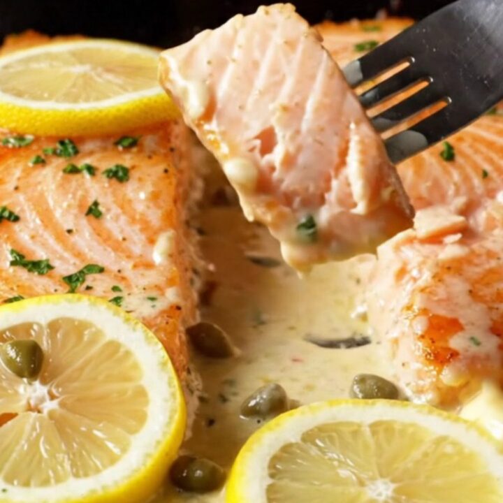 Crispy-skinned salmon fillets in a creamy lemon caper sauce, garnished with parsley