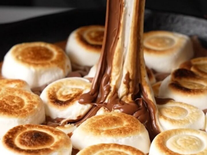 Cast iron skillet filled with melted chocolate, peanut butter chips, and toasted marshmallows