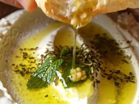 Turkish Haydari dip swirled on a plate, drizzled with mint butter and olive oil, with pita on the side