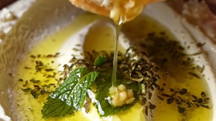 Turkish Haydari dip swirled on a plate, drizzled with mint butter and olive oil, with pita on the side