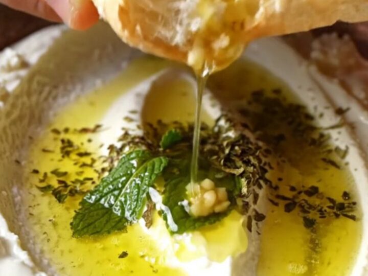 Turkish Haydari dip swirled on a plate, drizzled with mint butter and olive oil, with pita on the side