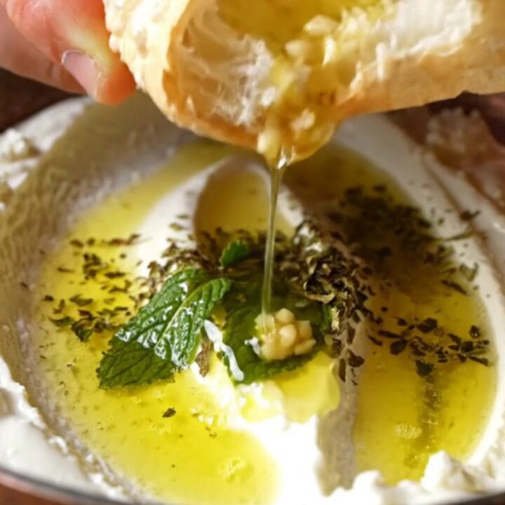 Turkish Haydari dip swirled on a plate, drizzled with mint butter and olive oil, with pita on the side