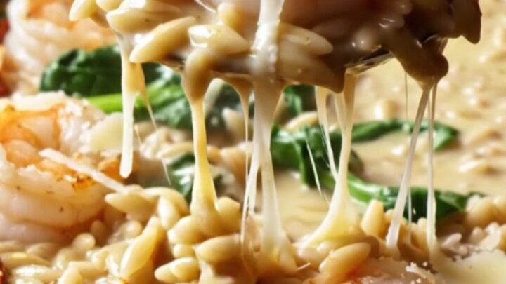 Creamy Tuscan garlic shrimp with orzo and spinach in a skillet, garnished with parmesan