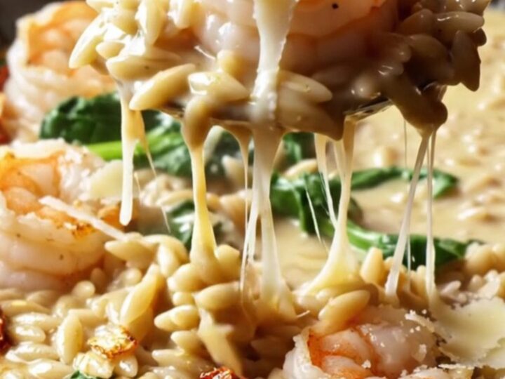Creamy Tuscan garlic shrimp with orzo and spinach in a skillet, garnished with parmesan